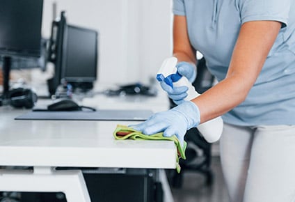 Kantoorbureau schoonmaken met spray en doek